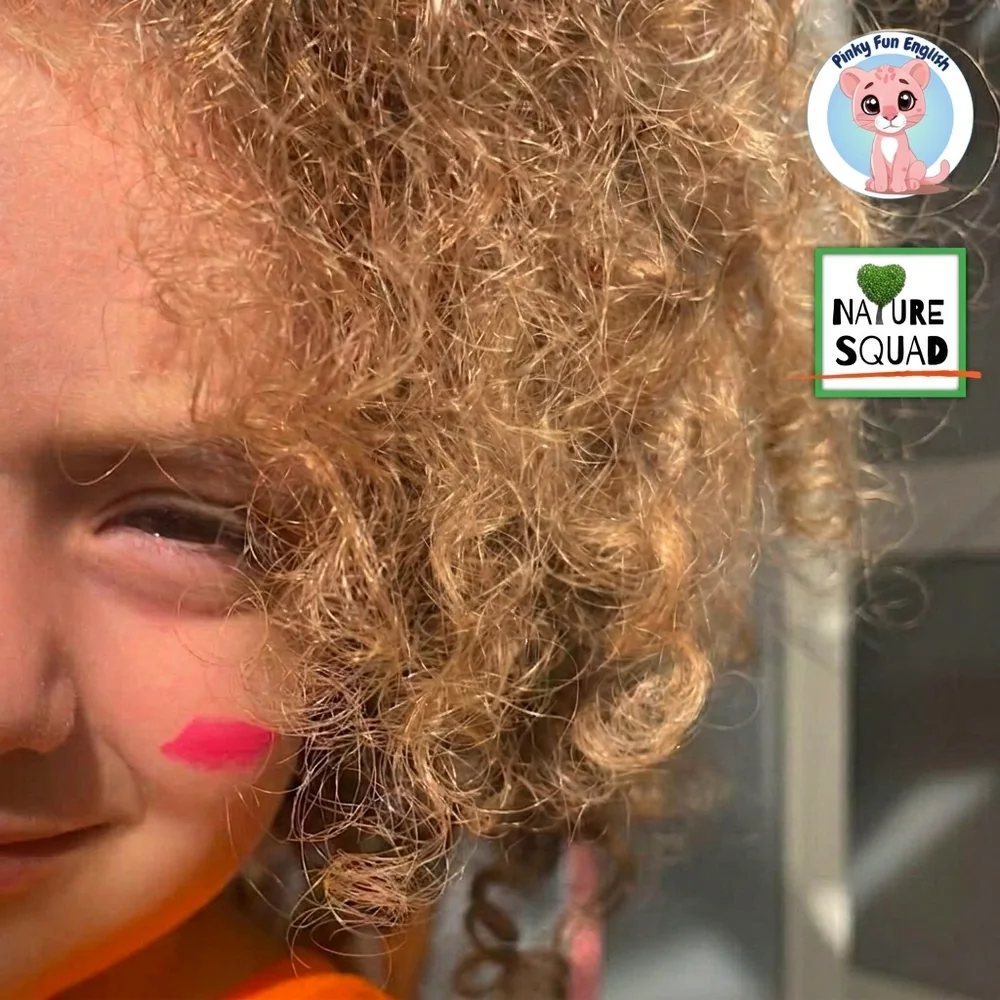 Una bambina con i capelli ricci, con i loghi Nature Squad® e Pinky Fun English® sulla foto