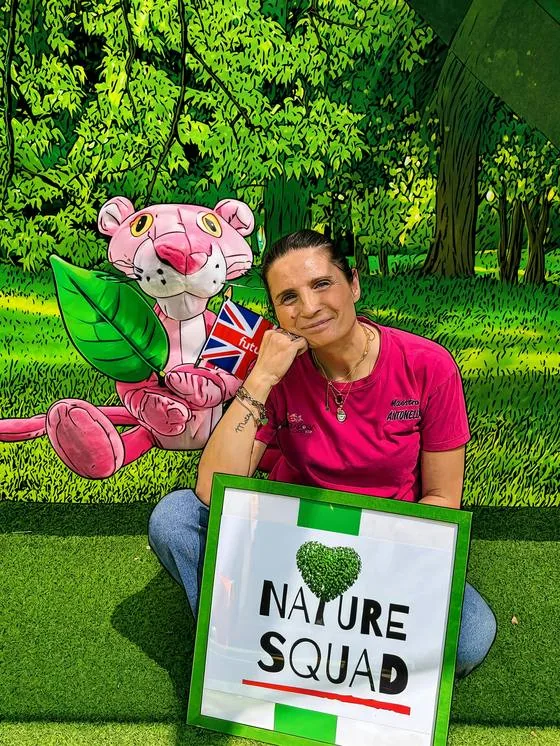 Antonella seduta sul prato con il cartello Nature Squad