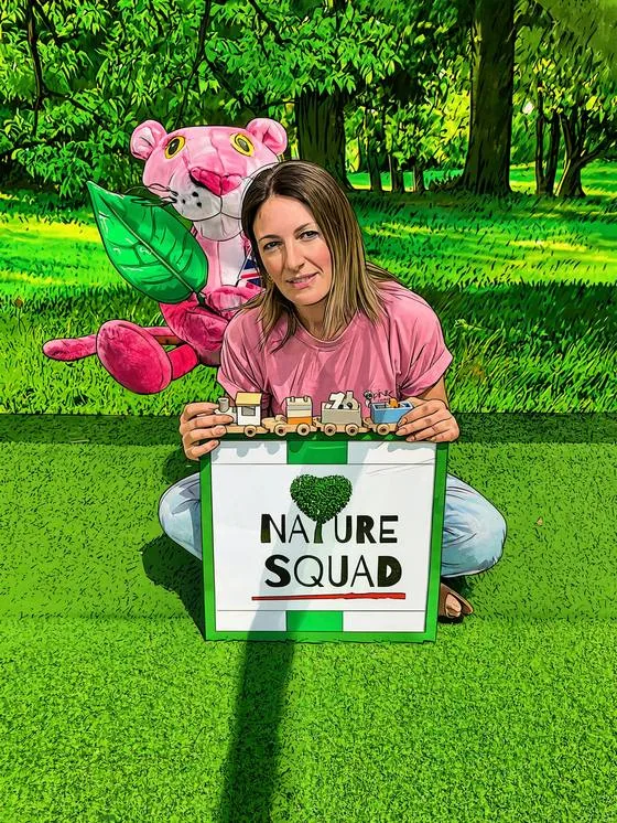 Anna seduta sul prato con il cartello Nature Squad