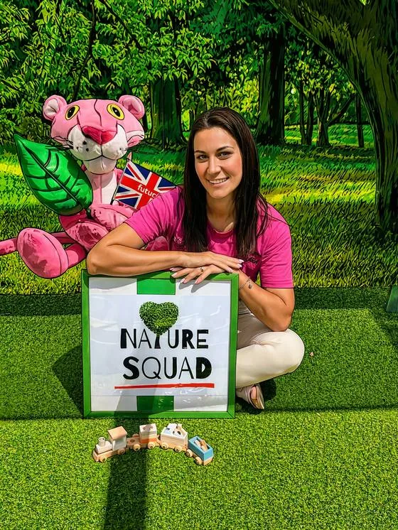 Sara seduta sul prato con il cartello Nature Squad